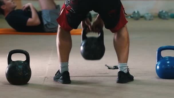 Entrenamiento deportivo: un hombre atlético con pantalones cortos rojos en cuclillas con un peso en las manos — Vídeos de Stock