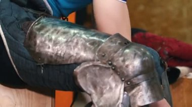 Şövalyeler antrenman yapıyor. Bir adam bacağına ve ayaklarına metal koruyucu takıyor.