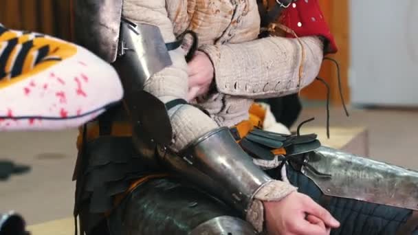 Knights training - a man putting on a metal armour on his elbows — Stock Video