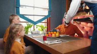 Otel restoranında oturan bir aile. Garson masaya şarap getiriyor.