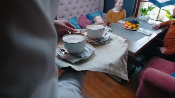 Úspěšná rodina sedící v hotelové restauraci - číšník přináší kávu ke stolu — Stock video