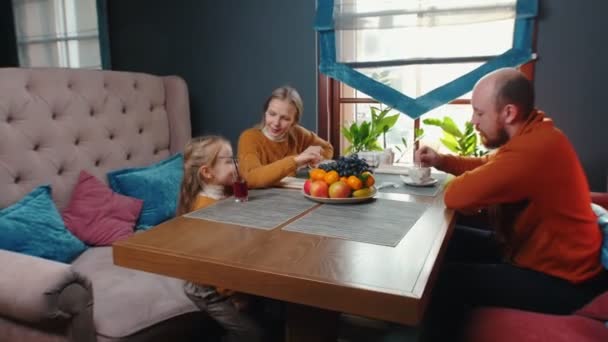 A family sitting in the hotel restaurant - a man and woman drinks coffee and their daughter drinking juice — Stock Video