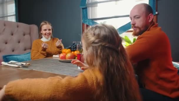 Een gezin in het restaurant van het hotel dat sap drinkt - een klein meisje zit naast haar moeder en knuffelt haar — Stockvideo