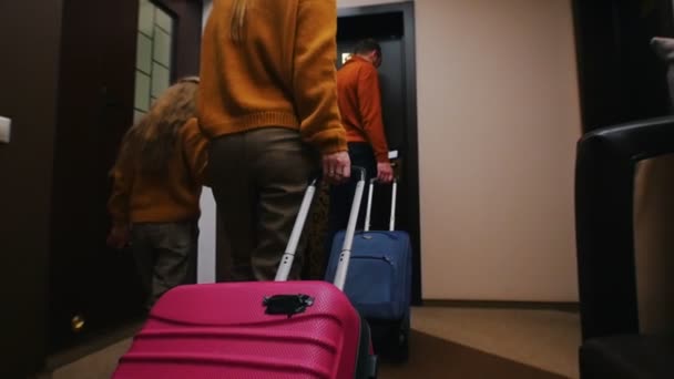 Eine junge Familie betritt ein Hotelzimmer - schleppt ihr Gepäck hinter sich her — Stockvideo