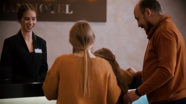 Um check-in familiar no hotel de luxo - uma mulher na recepção explica à família os seus privilégios no hotel — Vídeo de Stock