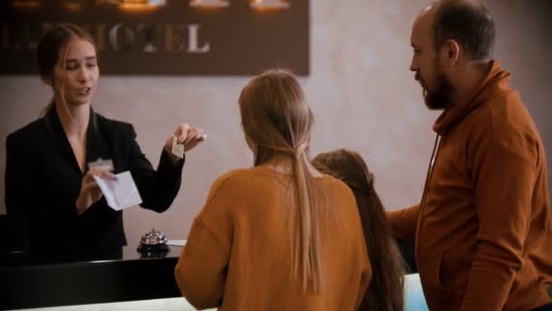 Un check-in familial à l'hôtel de luxe - une femme à la réception leur remet une brochure et les clés — Video