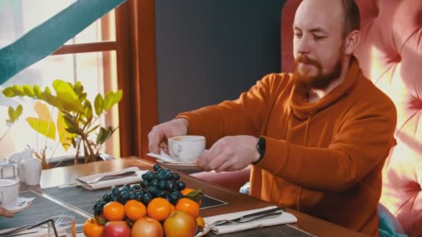 Famiglia seduta nel ristorante dell'hotel - un uomo e una donna che portano le tazze di caffè più vicino a loro — Video Stock