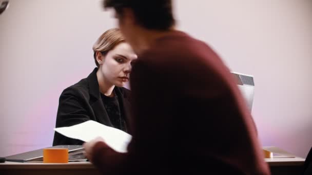 Un bureau qui travaille - une femme assise près de l'ordinateur - un homme vient la voir et lui remet un document - une femme déchire le papier et continue à travailler — Video