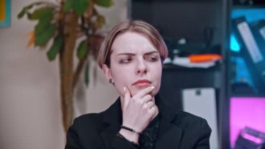 Ofiste bir şey düşünen genç bir iş kadını.
