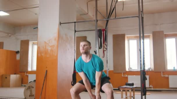 Sporttréning házon belül - egy jóképű férfi guggolva egy súllyal a kezében — Stock videók