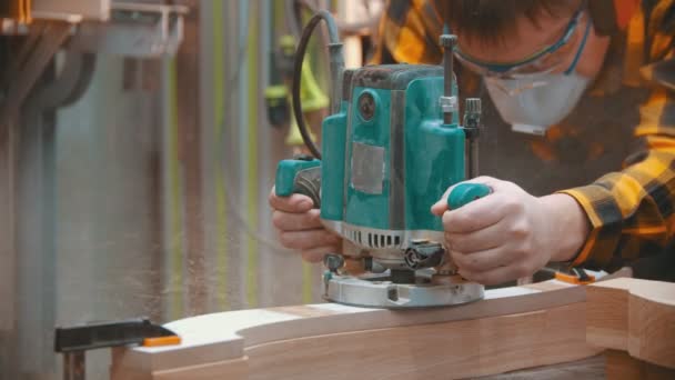 Carpintería interior: un carpintero hombre pule una plancha de madera con un equipo especial — Vídeos de Stock