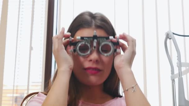 Oogheelkundige behandeling - een jonge vrouw zet een optometrie apparaat voor visie test — Stockvideo