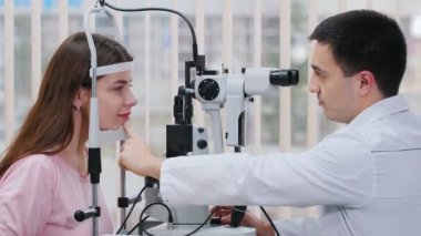 Oftalmoloji tedavisi- parlak dolaptaki özel bir aletle görsel keskinliğini kontrol eden genç ve güzel bir kadın - çenesini kürsüye çıkardı.