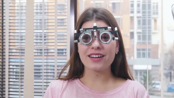 Oftalmologické ošetření - mladá usměvavá žena sedící v optometrii na vyšetření zraku — Stock video