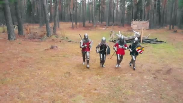 Quatro homens cavaleiros correndo na fila na floresta em armaduras de metal completo segurando espadas - dia — Vídeo de Stock