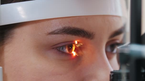 Augenheilbehandlung - eine junge Frau überprüft ihre Sehschärfe mit einem speziellen großen Optometriegerät - braune Augenfarbe — Stockvideo