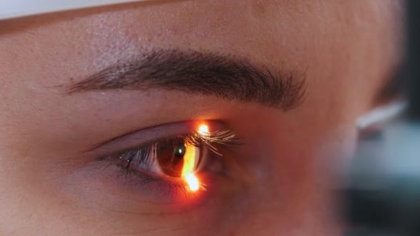 Молодая женщина, проверяющая свою остроту зрения при помощи света специальной большой оптометрической машины - коричневого цвета глаз — стоковое видео