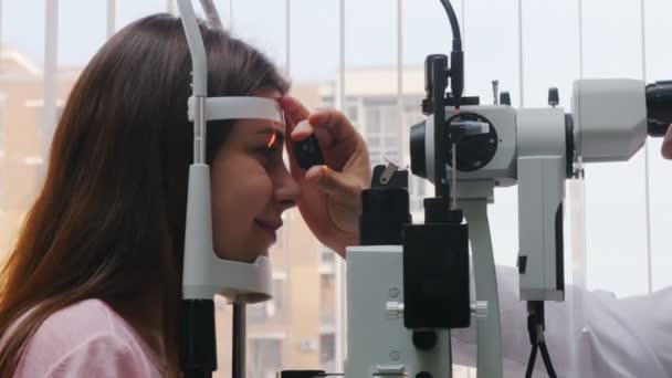 Офтальмологическое лечение - молодая женщина, проверяющая остроту зрения - реакция зрачка на свет бросает объектив — стоковое видео