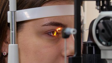 Oftalmoloji tedavisi - görme keskinliğini özel bir büyük optometri makinesi ile kontrol eden genç bir kadın - kahverengi göz rengi