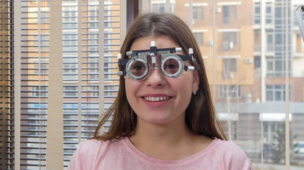 Augenheilbehandlung - eine junge lächelnde Frau sitzt im Optometriegerät für den Sehtest — Stockfoto