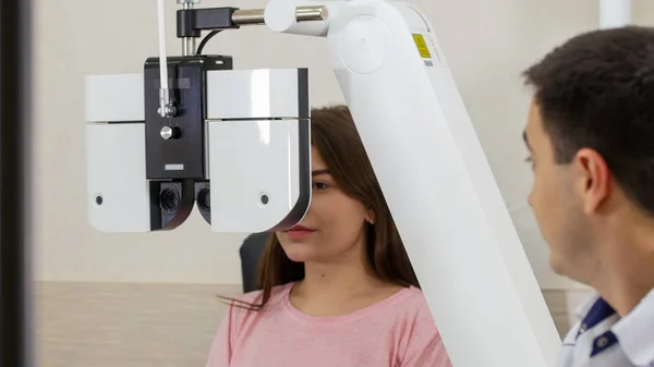 Augenheilkunde - eine junge Frau überprüft ihre Sehschärfe mit einem speziellen großen Optometrie-Gerät — Stockfoto