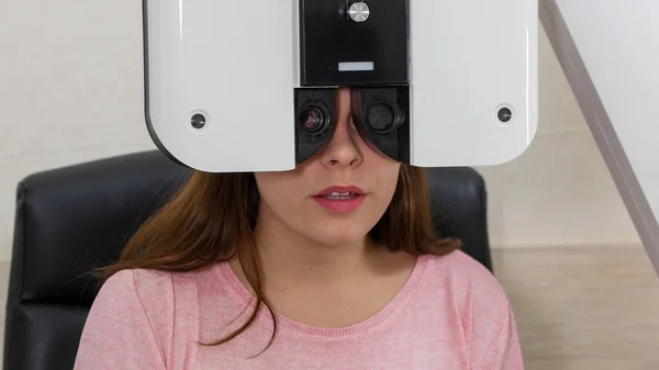 Ophthalmology treatment - 젊은 여성 이 특수 광학 기구로 시각적 예리 함을 확인하는 모습 — 스톡 사진