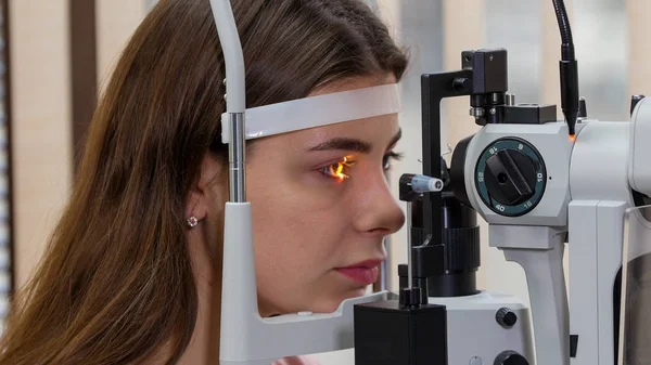 Tratamento oftalmológico - uma jovem mulher verificando sua acuidade visual com uma luz da grande máquina especial de optometria — Fotografia de Stock