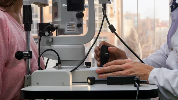 Οφθαλμολογική θεραπεία - ένας γιατρός που ελέγχει τις νεαρές γυναίκες οπτική οξύτητα με ένα ειδικό μηχάνημα σε ένα ευρύχωρο ντουλάπι — Φωτογραφία Αρχείου