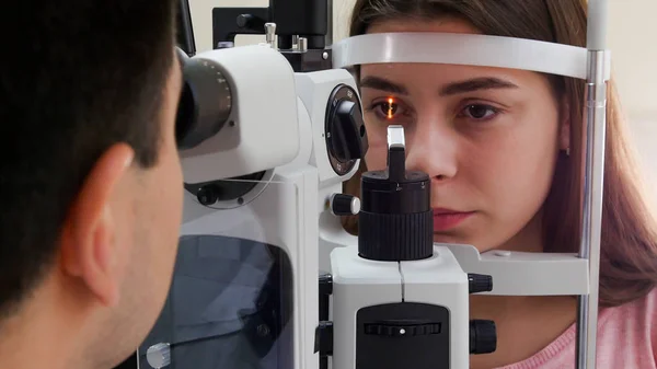 Augenärztliche Behandlung - eine junge Frau mit rosa Lippen überprüft ihre Sehschärfe - Pupillenreaktion auf Licht — Stockfoto