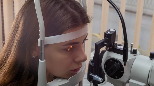 Traitement ophtalmologique - une jeune femme vérifiant son acuité visuelle avec - réaction de la pupille à la lumière jeter la lentille — Photo