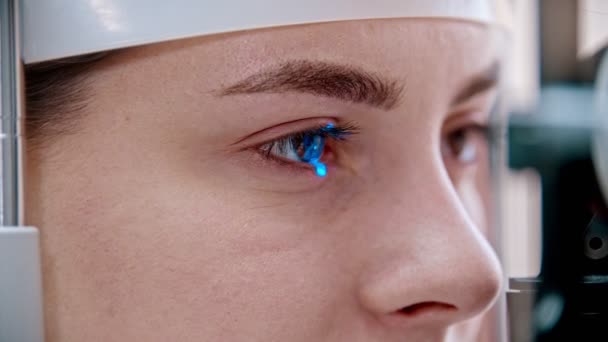Tratamento oftalmológico - uma jovem mulher verificando sua acuidade visual com uma luz colorida diferente da grande máquina especial de optometria - cor dos olhos castanhos — Vídeo de Stock