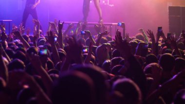 Konserde elleri havada dans eden enerjik insanlar - mor ışık