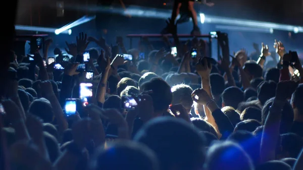 Gente enérgica bailando con las manos en alto en el concierto punk - iluminación azul — Foto de Stock