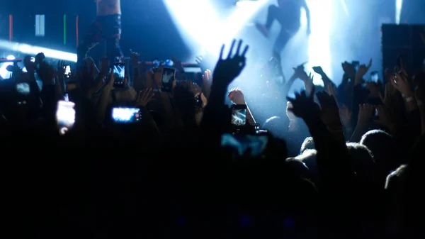 Multidão energética dançando com as mãos para cima no show punk - iluminação azul — Fotografia de Stock