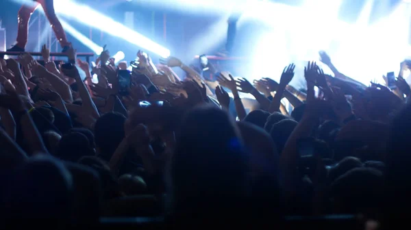 Energiczni ludzie tańczący z rękami w górze na koncercie rockowym — Zdjęcie stockowe