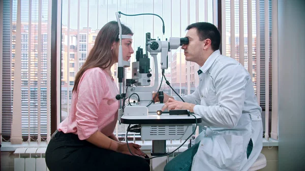 Ophthalmology treatment - young pretty smiling woman checking her visual acuity with a special equipment in the spacious cabinet — 스톡 사진