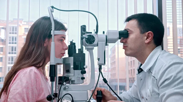 Oftalmologia - jovem verificando sua acuidade visual com um equipamento especial no armário espaçoso — Fotografia de Stock
