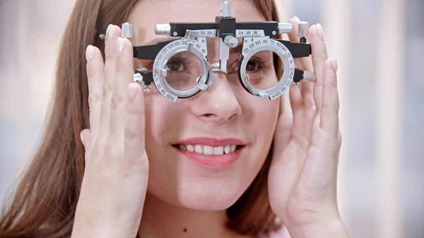 Traitement ophtalmologique - une jeune femme souriante enfilant un appareil pour un test de vision — Photo