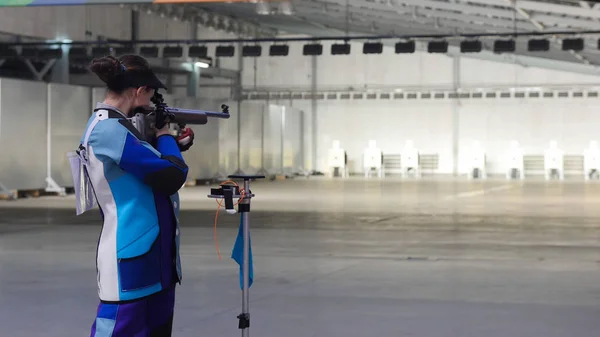 BULLET SHOOTING. girl in a blue suit is aiming at a target — Stock Photo, Image