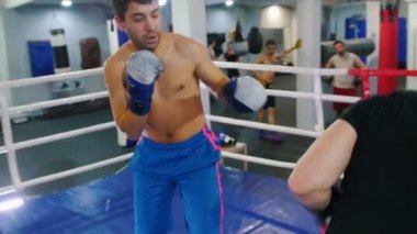 Kapalı alanda boks. Siyah tişörtlü bir adam boks ringinde kavga ediyor.
