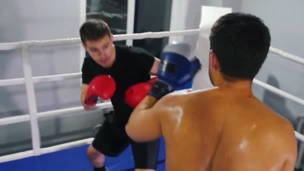 Boxe dentro de casa - dois homens tendo uma luta de treinamento no ringue de boxe — Vídeo de Stock