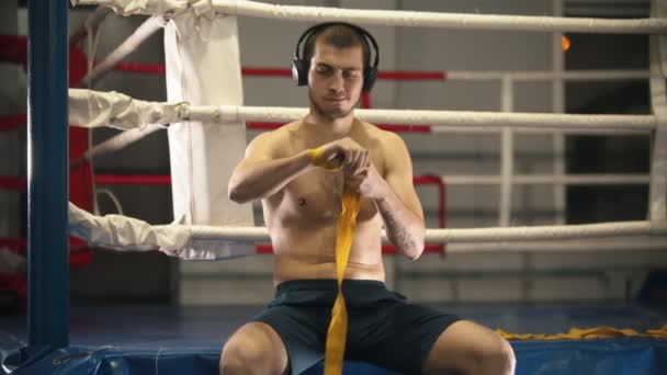 Box trénink - muž sedící na ringu a obvazuje si ruce — Stock video