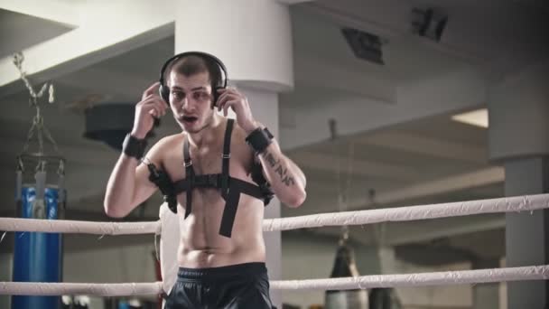 Box training - een bezwete man zet een koptelefoon op en begint te trainen - schaduwvechten met bandage — Stockvideo