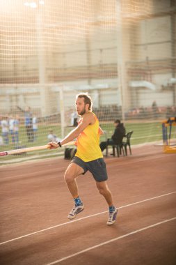 Spor stadyumunda sırıkla atlama - pistte koşan atletik bir adam