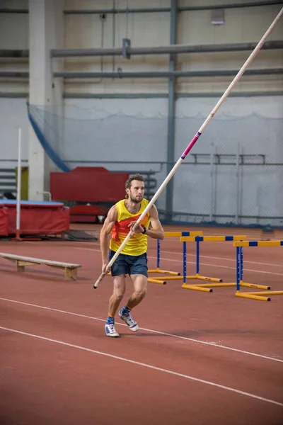 Pólo abóbada dentro de casa - um homem de camisa amarela prestes a correr na pista com um pólo — Fotografia de Stock