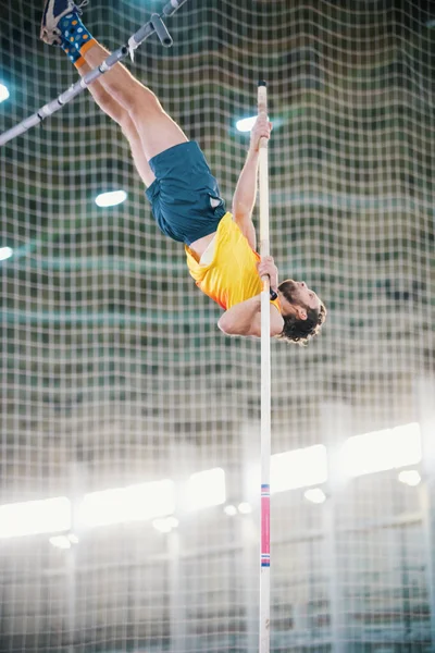 Прыжки с шестом - спортсмен, прыгающий через стойку - опирающийся на столб — стоковое фото