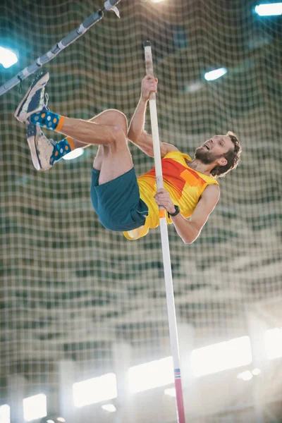 Stabhochsprung im Sportstadion - ein athletischer Mann springt über die Latte — Stockfoto