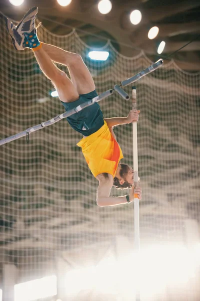 Entrenamiento de salto de poste en el estadio deportivo: un hombre atlético saltando sobre el bar —  Fotos de Stock