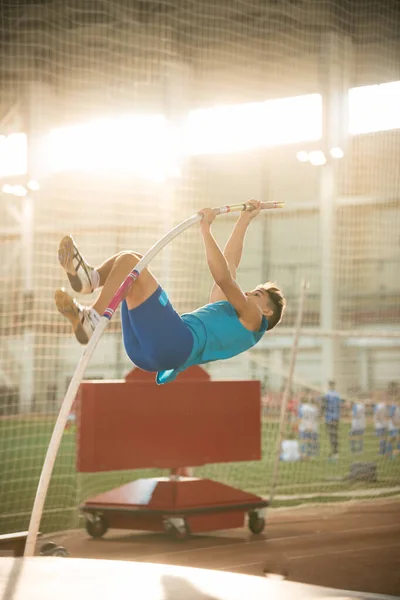 スポーツスタジアムでのポールボールトトレーニング-若いフィット男がバーを飛び越える — ストック写真