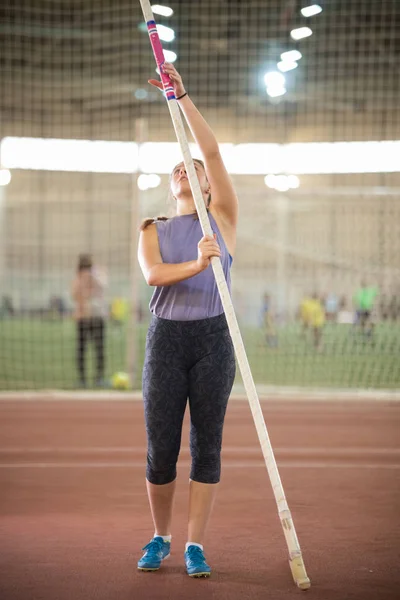 Entrenamiento de bóveda de poste en el estadio deportivo: una joven deportista con coletas en la pista sosteniendo un poste — Foto de Stock